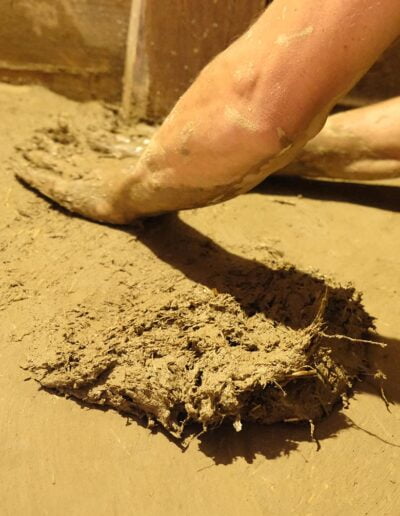 Vályog képzés a sármíves alapok. Józsa Fruzsina vályogszakértő előadó keze simítja a vályog tapasztást.